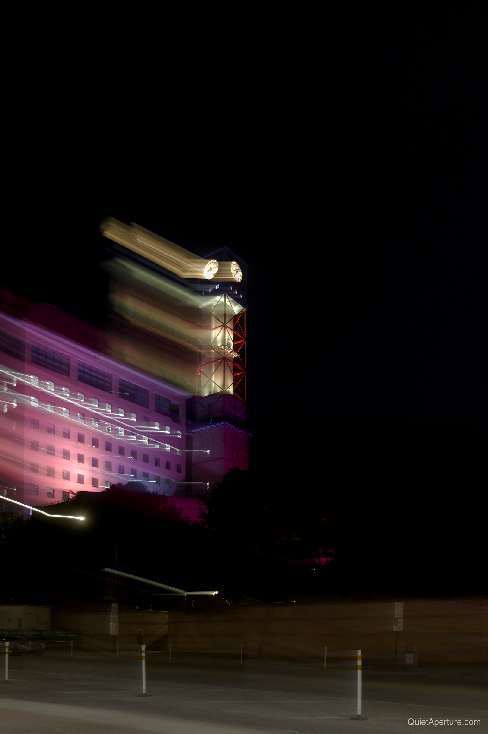 An illuminated clock tower traced with streaks of light, frame 02.