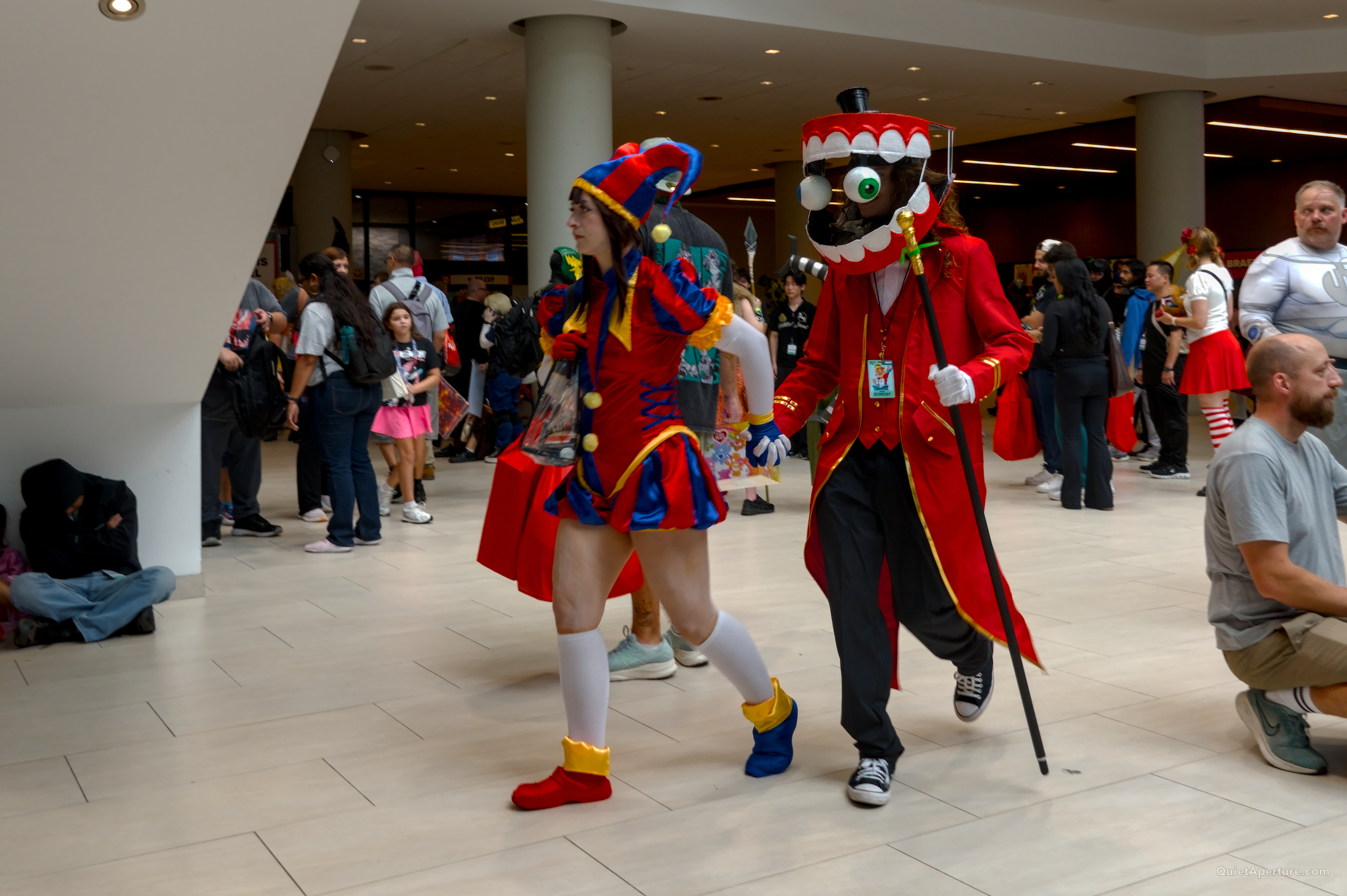 Two costumed Fan Expo attendees walking through a busy convention hall.