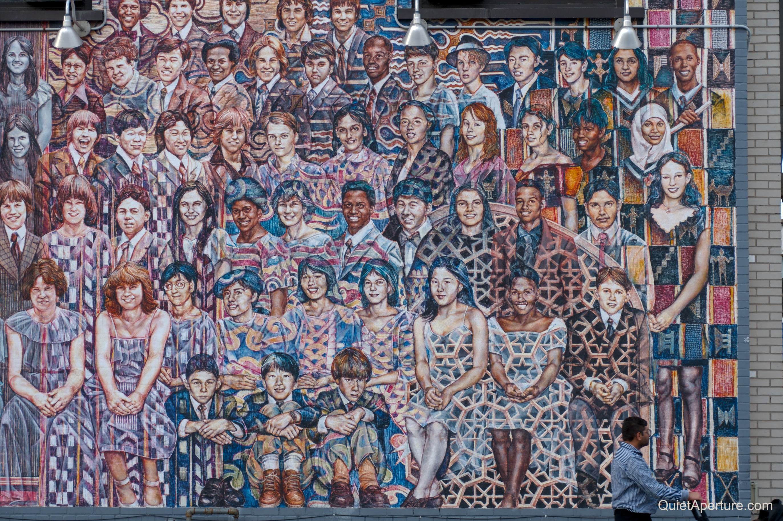 A large mural filled with rows of painted community portraits.